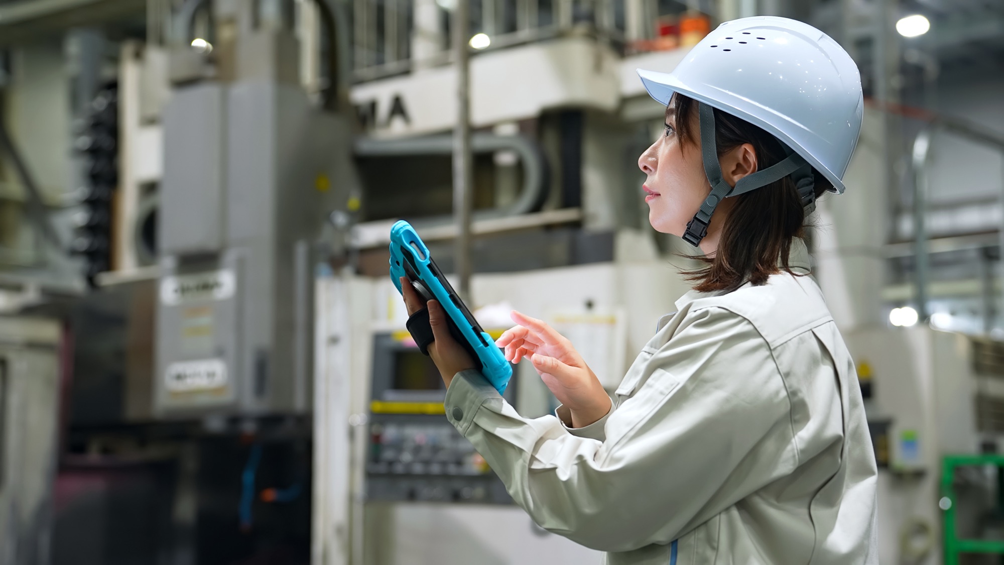 工場でタブレットを使い設備を確認する作業者